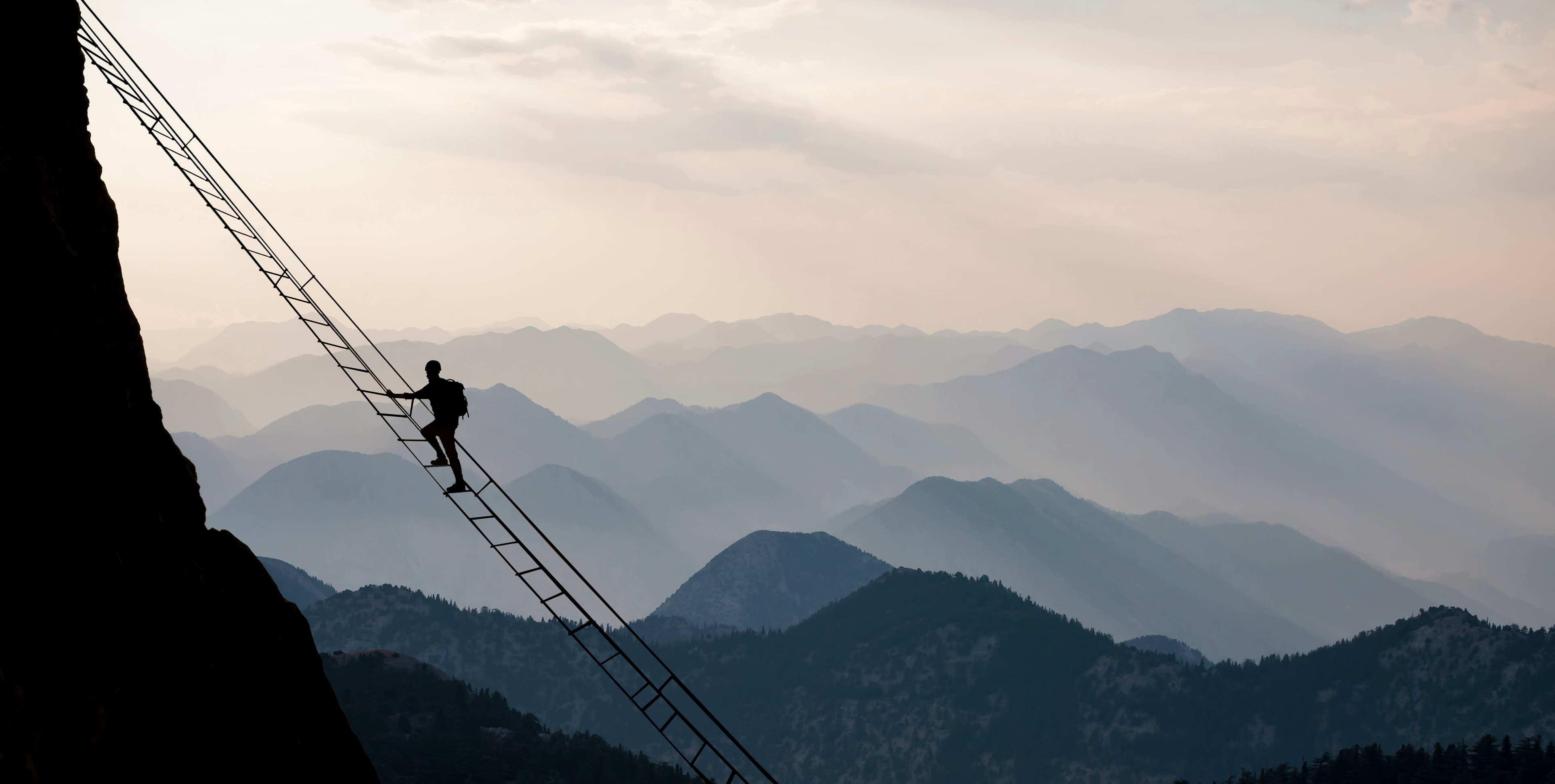 Person climbing a ladder up the side of a cliff